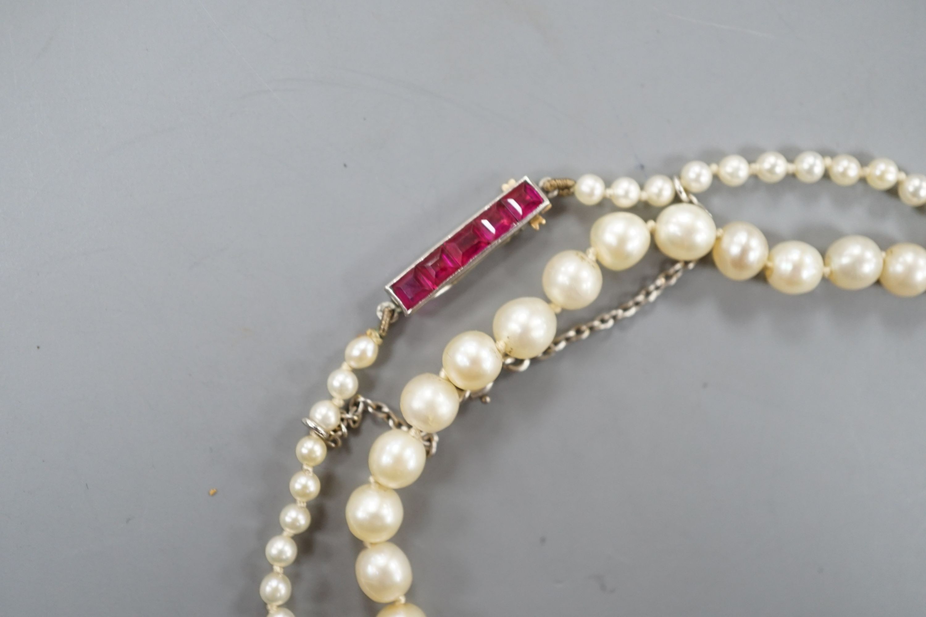 An early 20th century single strand graduated pearl necklace(pearls have not been tested as to whether or not they are natural), five stone ruby set yellow metal clasp, 44cm, gross weight 8.7 grams